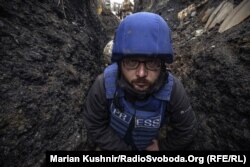 Serhiy Nuzhnenko, fotoreporter la Serviciul ucrainean al RFE/RL, într-o tranșee lângă satul Pivdenne, în regiunea Donetsk din estul Ucrainei, în aprilie 2022. El și Marian Kușnir, jurnalist RFE/RL, au fost forțați să se ascundă într-un șanț din cauza tirurilor de mortiere rusești