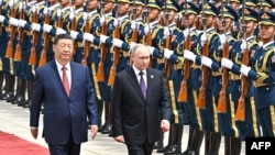 Președintele rus Vladimir Putin (d) și liderul chinez Xi Jinping sunt salutați de garda de onoare militară în timpul unei ceremonii oficiale de bun venit la Beijing, în mai 2024.