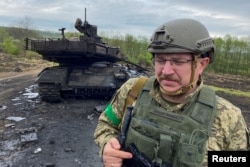 Украинский военнослужащий на фоне уничтоженного российского танка Т-90М «Прорыв» в Харьковской области, май 2022 года