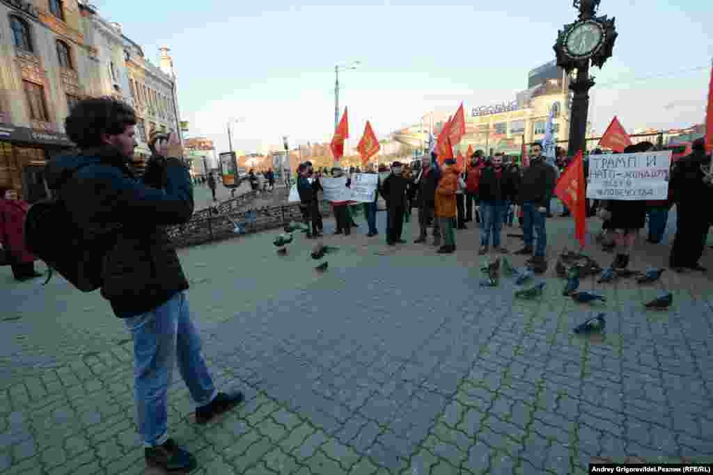 Иностранная молодежь позирует на фоне плакатов и красных флагов 