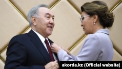 Председатель сената парламента Казахстана Дарига Назарбаева награждает своего отца, экс-президента Казахстана Нурсултана Назарбаева знаком почетного сенатора. Нур-Султан, 6 июля 2019 года.