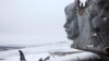 A man and a child walk in the snow at the destroyed war memorial at Savur-Mohyla, a hill east of the city of Donetsk, December 7, 2014