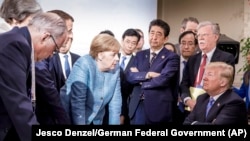 Scena cu Donald Trump stând sfidător cu brațele încrucișate în fața liderilor mondiali a avut loc la summit-ul G7 din 2018.