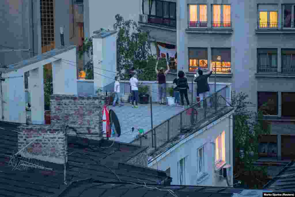 Locuitorii din Belgrad fac zgomot în timp ce stau pe acoperișul unei clădiri la un protest de 1 mai față de măsurile de carantină de adoptate de guvernul Serbiei.