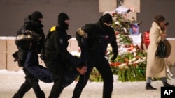 Ofițerii ruși de poliție l-au reținut pe un bărbat care depunea flori pentru Alexei Navalnîi la Memorialul Victimelor Represiunii Politice din Sankt Petersburg, orașul de baștină al președintelui rus Vladimir Putin - 16 februarie 2024. 
