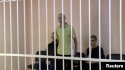 Bританците Ейдън Аслин и Шон Пинер и мароканецът Брахим Саадун в съдебна зала, за която се твърди, че е в Донецк
