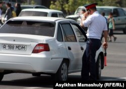 Көліктің қасында тұрған жол полициясы өкілі.
