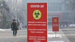 Мужчина идет по улице на фоне стендов с надписями, призывающими носить маски. Алматы, 4 января 2021 года.