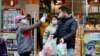 A worker measures body temperature of people leaving a supermarket in Qingshan district following an outbreak of the novel coronavirus in Wuhan, Hubei province, China February 7, 2020. Picture taken February 7, 2020. China Daily via REUTERS  ATTENTION EDI