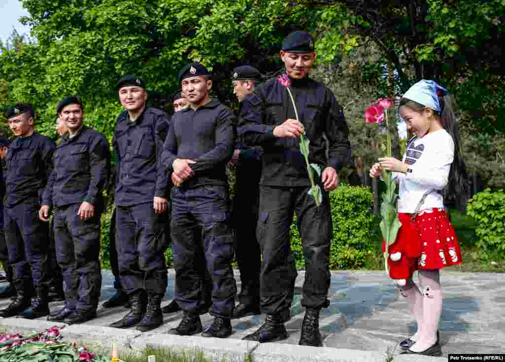 Маленькая девочка дарит цветок полицейскому во время протестов в день единства народов Казахстана в Алматы, 1 мая 2019 года. (Petr Trotsenko, RFE/RL)