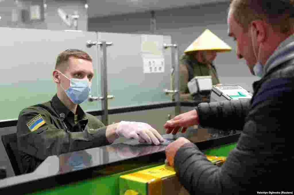 An officer of the Ukrainian State Border Guard Service checks the passport of a passenger who had just arrived in Kyiv from China.